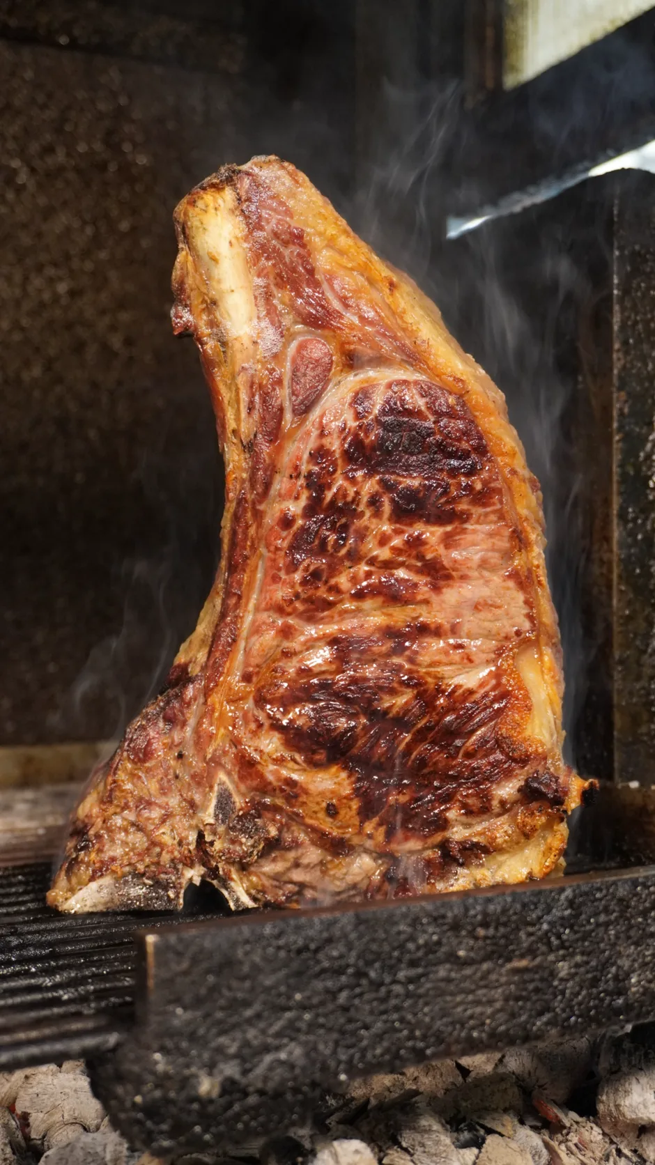 Il bisteccone in piedi sulla brace, col fumo che sale